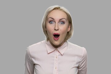 Happy stunned woman on gray background. Young excited woman close up. Human facial expressions and...