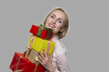 Happy woman with gift boxes on gray background. Beautiful smiling woman received many gifts for Birthday. End of the year bonus.