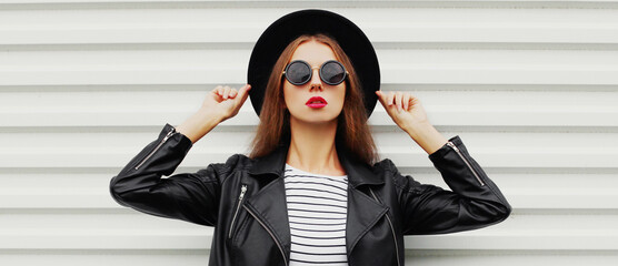 Portrait of stylish young woman wearing a black round hat, jacket on a white background