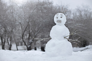 snowman on the street, children made a snowman out of snow and branches, children's winter fun,...