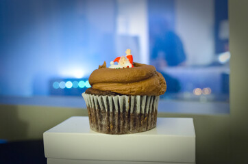 Close Up of a Tasty Chocolate Christmas Cupcake with a Little Santa Claus on Top. Blurry New York City Lights in Background