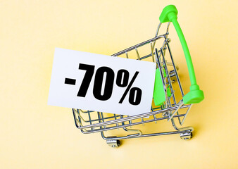 The card with the words MINUS SEVENTY PERCENT is in the shopping cart. Marketing concept