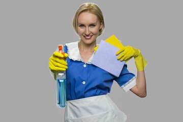 Housekeeper in uniform holding cleaning supplies. Pretty smiling chambermaid with rags and...