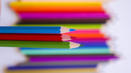 Beautiful colored pencils on a blurred background of multicolored wooden colors.