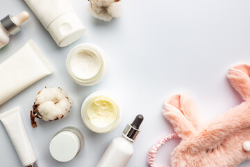 Cosmetic white containers with sleep mask on white background top view. Skin night care products. Hand, face, body moisturizing cream jar.