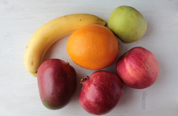 Orange, mango, apple and banana lying on the surface of the light.