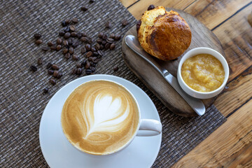 Vista superior de una taza de caf&eacute; capuchino y pan con mermelada sobre una mesa