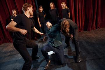 Fototapeta na wymiar Fight scene. Group of actors in dark colored clothes on rehearsal in the theater