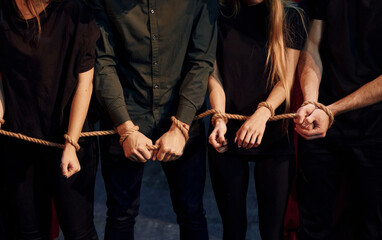 With rope in hands. Group of actors in dark colored clothes on rehearsal in the theater