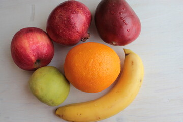 Fototapeta na wymiar An orange, apples and banana lie on a light wooden surface.