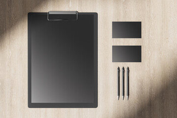 Wooden desktop with blank black clipboard