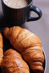 Croissants on a gray tablecloth with cappuccino