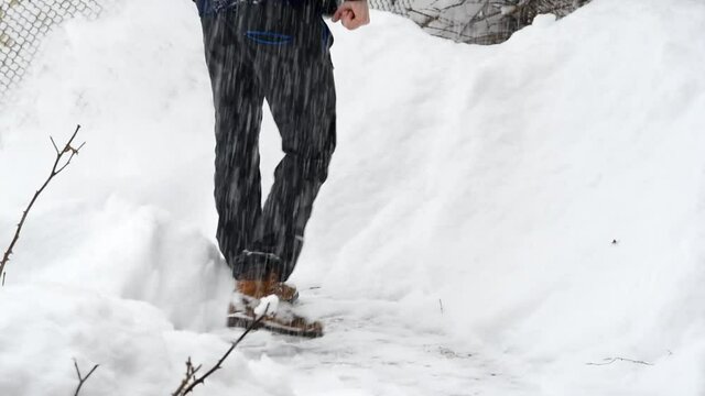 un uomo mentre pulisce la strada dalla neve con un badile durante una grande nevicata