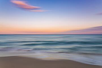 Fototapeta na wymiar Palm Beach Island beach sunset with slow shutter pan of pink, blue and purple skies with green ocean water