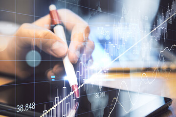Businessman hand with pen using tablet with business charts.