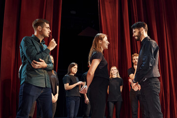 Two people talking. Group of actors in dark colored clothes on rehearsal in the theater