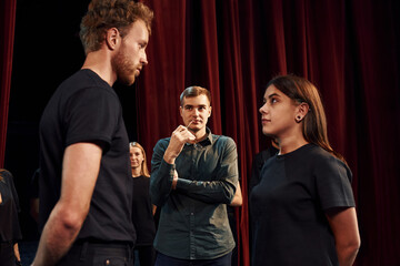 Two people talking. Group of actors in dark colored clothes on rehearsal in the theater