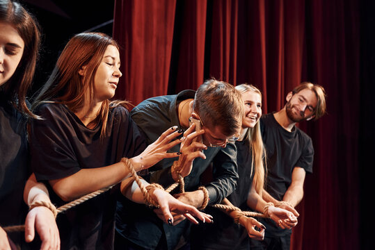 Knot in the hands. Group of actors in dark colored clothes on rehearsal in the theater
