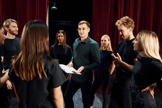Group of actors in dark colored clothes on rehearsal in the theater