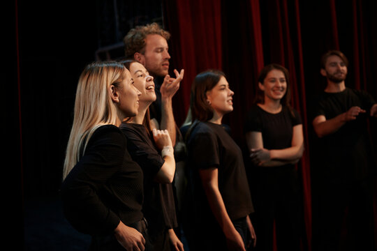 Side view. Group of actors in dark colored clothes on rehearsal in the theater