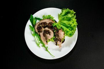 Bitten sandwich with baked meatloaf and herbs, with salad leaves and arugula for a snack on a white plate on black background.