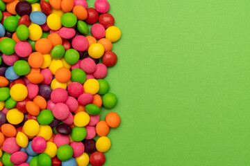 Obraz premium Many colorful candies on green background