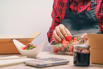 Owner packing fruit and product in the carton box at home and preparing a parcel for delivery at online selling business