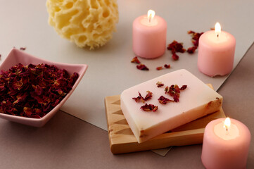 Romantic bath accessories arrangement with rose handmade soap, pink candles and rose petals.