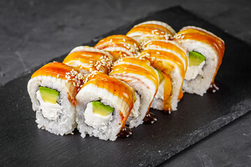 appetizing Philadelphia sushi roll with eel and avocado on a black stone plate