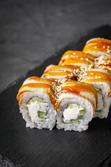 appetizing Philadelphia sushi roll with eel and cucumber on a black stone plate