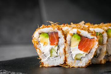 appetizing philadelphia sushi roll with tuna salmon avocado chips and cucumber on a black stone plate