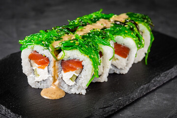 appetizing sushi roll with philadelphia cheese cucumber salmon and chuka on a black stone plate