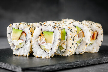 appetizing sushi roll california with eel avocado cucumber and sesame seeds on a black stone plate