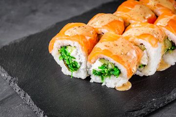 appetizing sushi roll philadelphia with salmon cucumber and chuka on a black stone plate