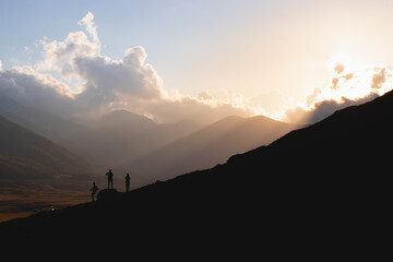 Silhouette of three men at sunset in the mountains 