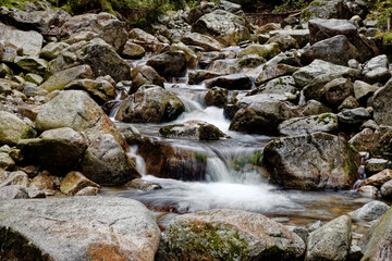 Water flowing in rocks in wild mountains river. Waksmundzki stream raging in High Tatras Mountains in Poland.