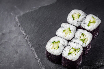 appetizing sushi roll maki with cucumber on a black stone plate