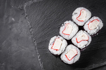 appetizing sushi roll maki with crab stick on a black stone plate © Narsil