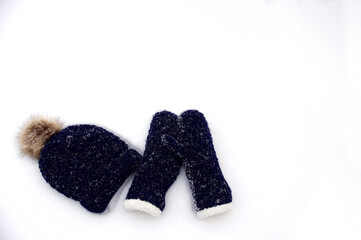 dark blue knit mittens and hat in white snow with copy space