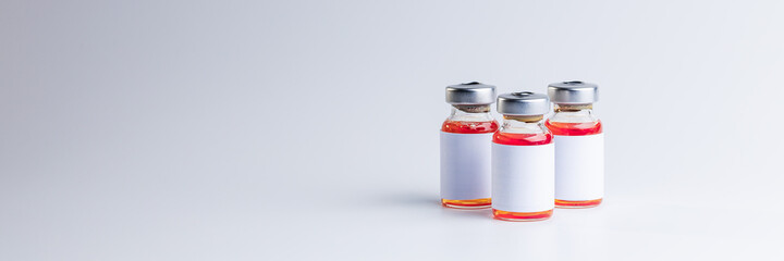 blank medical vaccine vials with red liquid over gray background. vaccination concept. copy space. isolated