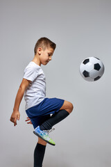 boy professionally training with soccer ball in studio, preparing for competition, game, wearing special uniform. isolated portrait