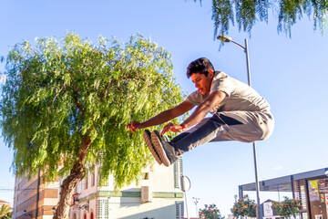 Active Latino young man jumping in action. Extreme sport activity, parkour outdoor free running or healthy lifestyle concept