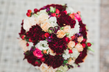Beautiful toned picture with wedding rings against the background of a bouquet of flowers