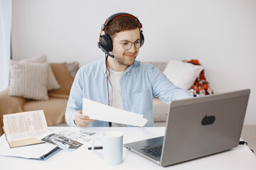 Man sitting in living room at home. Guy enjoying studying using laptop and headset.