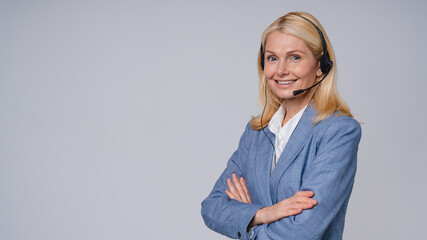 Confident mature call center worker wearing headphones and formal clothing isolated over grey...