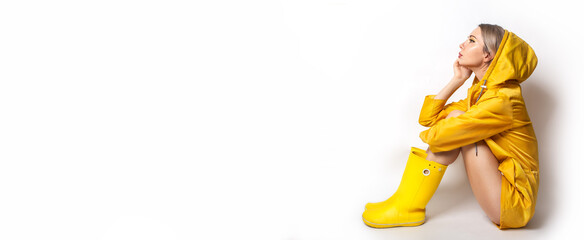 Horizontal banner with young woman in illuminating yellow slicker and rubber boots. Fashion blonde...