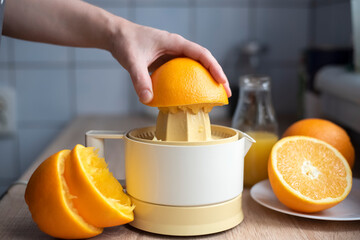 Female hand squeezing orange juice.