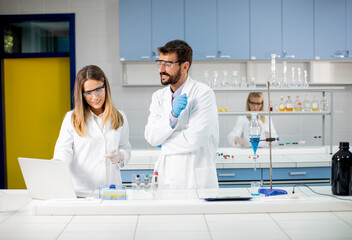 Researchers working with blue liquid at separatory funnel