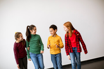 Naklejka premium Portrait of cute little kids in jeans talking and smiling, walking by white wall