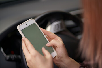 Mockup image of a woman holding, using mobile phone with blank screen while driver a car.